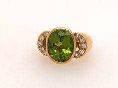 This vintage Italian-made peridot ring is a remarkable piece, reflecting timeless elegance and fine craftsmanship. Fashioned from solid and heavy 18k yellow gold, the ring showcases a classic bezel setting that securely encases the oval peridot.  Five round brilliant cut diamonds on each side of the oval peridot, making a total of ten diamonds. The ring's design is accentuated by a carefully crafted gallery beneath the stones, allowing light to flow through and enhance the natural brilliance of the peridot and diamonds. The substantial weight and sturdy construction speak to its durability, while the vintage charm adds a unique character to this luxurious piece. Specs:  Stamped 18k and M Genuine peridot and diamonds  Size 6 1/2 finger size Peridot Ring, Diamond Sizes, Precious Gemstones, Vintage Italian, Round Brilliant Cut Diamond, Bezel Setting, Gemstone Ring, Semi Precious Gemstones, Rings Statement