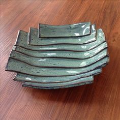 a stack of green dishes sitting on top of a wooden table