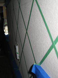 there is a blue tape on the wall next to some green lines and a light switch