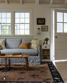 a blue and white checkered couch in a living room with two windows above it