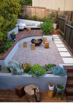 an outdoor patio with wooden steps, gravel and plants on the side of the building