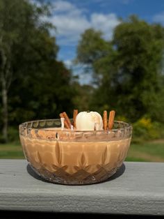 a glass bowl filled with food sitting on top of a wooden table next to trees