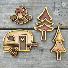 three wooden cut outs depicting campers, trees and a camper trailer on a wood background