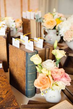 there are many books and vases with flowers in them sitting on the table next to each other