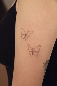 a woman's arm with two small butterflies on the left side of her arm