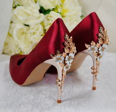 a pair of red high heeled shoes sitting on top of a table next to flowers