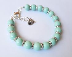 a green bracelet with silver beads and a heart charm