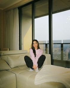 a woman sitting on top of a couch next to a window