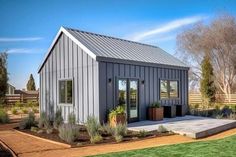 a small gray house sitting on top of a lush green field