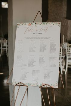 a seating chart is displayed on a stand in front of tables and chairs at a wedding reception