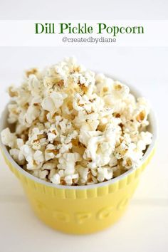 a yellow bowl filled with popcorn sitting on top of a white table next to a green sign that says dill pickle popcorn