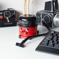 a red and black camera sitting on top of a white table next to a keyboard