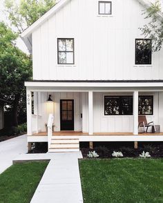 a white two story house with porches and steps leading up to the front door