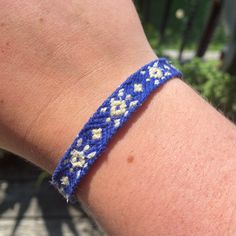 a close up of a person wearing a blue and white bracelet with flowers on it