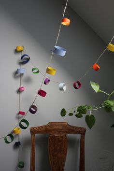 some paper cups are hanging from a string on a chair in front of a wall