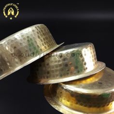 three metal bowls stacked on top of each other in front of a black background with gold dots