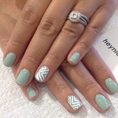 a woman's hands with green and white nail polish