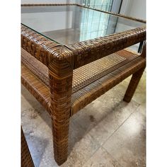 a wicker table with glass top and two benches on the bottom, in front of a window