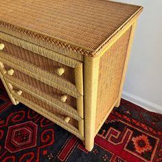 an old wicker chest on carpeted floor next to white wall and red rug