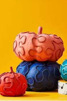 three brightly colored pumpkins sitting next to each other on top of a yellow surface