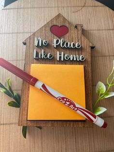 a wooden sign that says no place like home with a pen and envelope next to it