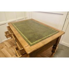 a wooden table with drawers and a green rug on top of it in a room