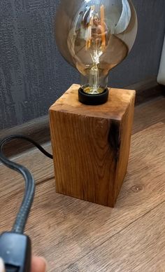 a person holding a light bulb on top of a wooden block with a cord attached to it