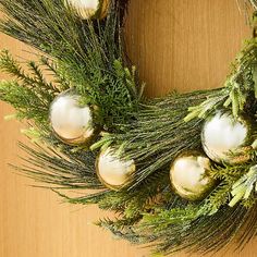 a christmas wreath with ornaments hanging from it's sides on a wooden table top