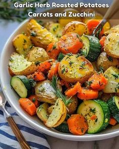 garlic herb roasted potatoes, carrots and zucchini in a white bowl with a fork