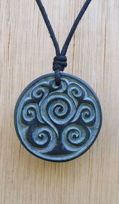 a black pendant with swirls on a string