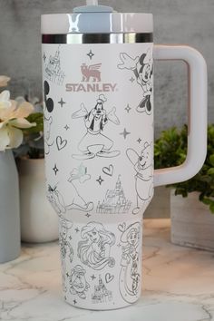 the travel mug is decorated with many disney characters and names on it's side