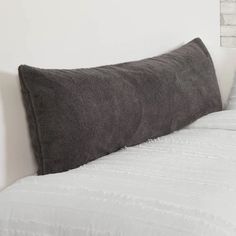 a gray pillow sitting on top of a bed next to a white brick headboard