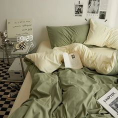 an unmade bed with green sheets and pillows on top of it next to a checkered floor