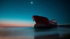 a large boat floating on top of a body of water under a moon lit sky