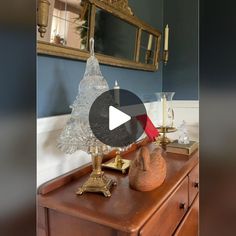 an old dresser with a glass christmas tree on top and candles in vases next to it