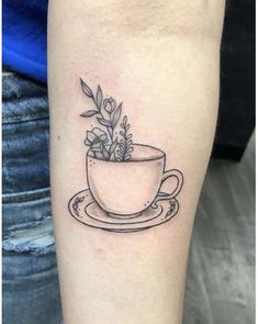 a small cup with a plant in it on the left forearm and an arm tattoo