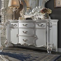 an ornate white dresser and mirror in a room with gray walls, rugs and lamps