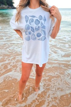 "Our Comfort Colors sea shell shirt features a variety of vintage sea shell drawings in blue ink.  Our Comfort Color tees are soft and very comfy! They're made from medium weight 6.1 oz/yd 100% USA-grown ring-spun cotton, and are pre-shrunk and pigment-dyed. Pigment dyes provide a great vintage look. We use a direct to garment printing method to ensure a lasting graphic print that won't peel or rub off (no vinyl!).  These tees come in unisex sizes and have a RELAXED fit. For an oversized look, p Blue Nautical Style T-shirt For Summer, Nautical Short Sleeve Beach Top, Nautical Cotton Tops For The Beach, Blue Short Sleeve Tops For Beachwear, Blue Nautical T-shirt For Summer, Nautical Blue T-shirt For Summer, White Nautical Tops For Vacation, Nautical Beach Tops For Summer, Nautical Tops For Beach In Summer