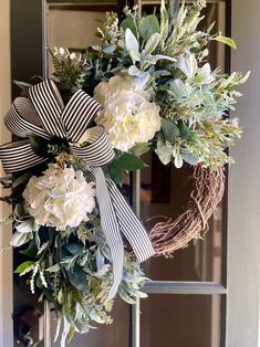 a wreath with white flowers and greenery hangs on the front door