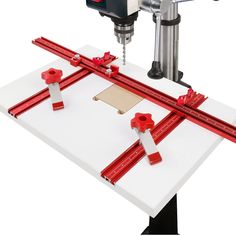 a machine that is cutting some red tape on a piece of paper with a driller