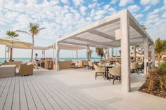 an outdoor dining area with tables and umbrellas on the deck next to the ocean