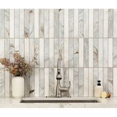 a kitchen sink sitting under a faucet next to a white tiled wall