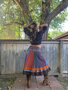 a woman with dreadlocks standing in front of a tree