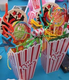 three popcorn boxes are sitting on a table with candy sticks and candies in them