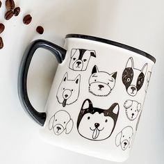 a black and white coffee mug with dogs on it, surrounded by coffee beans in the background