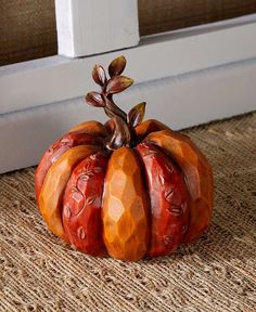 an orange pumpkin sitting on the ground next to a window