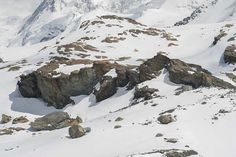 a man riding skis down the side of a snow covered slope on top of a mountain