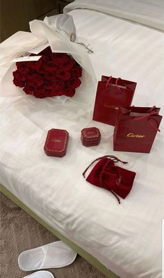 red roses are laid out on a bed with white sheets and paper bags next to them