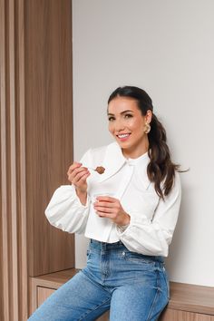 a woman sitting on top of a wooden cabinet holding a piece of paper in her hand