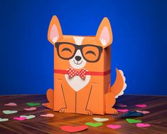 an origami dog with glasses and a bow tie sits on a table surrounded by confetti